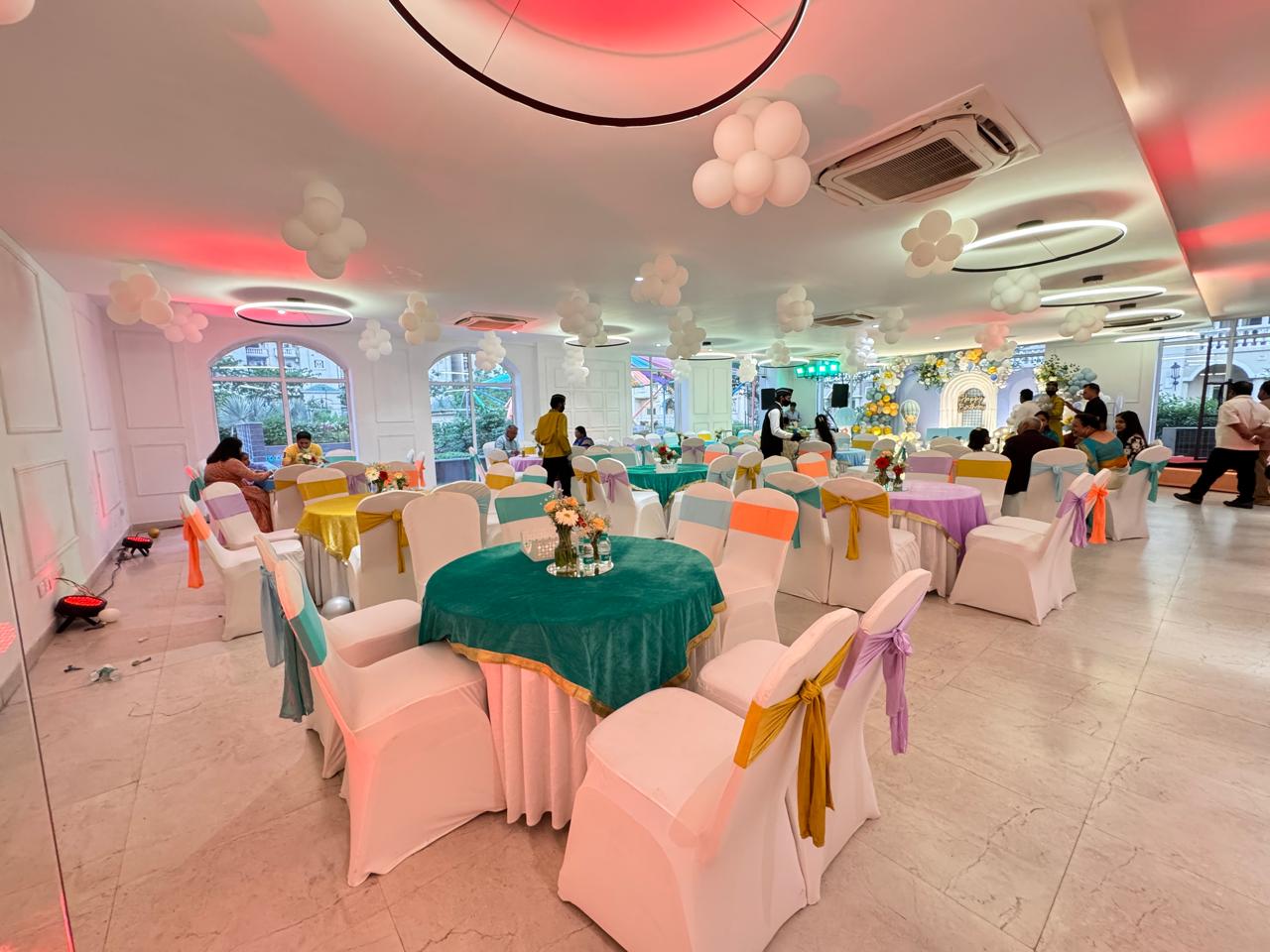 Decorated banquet hall with balloon clusters and colorful table settings in Greater Noida