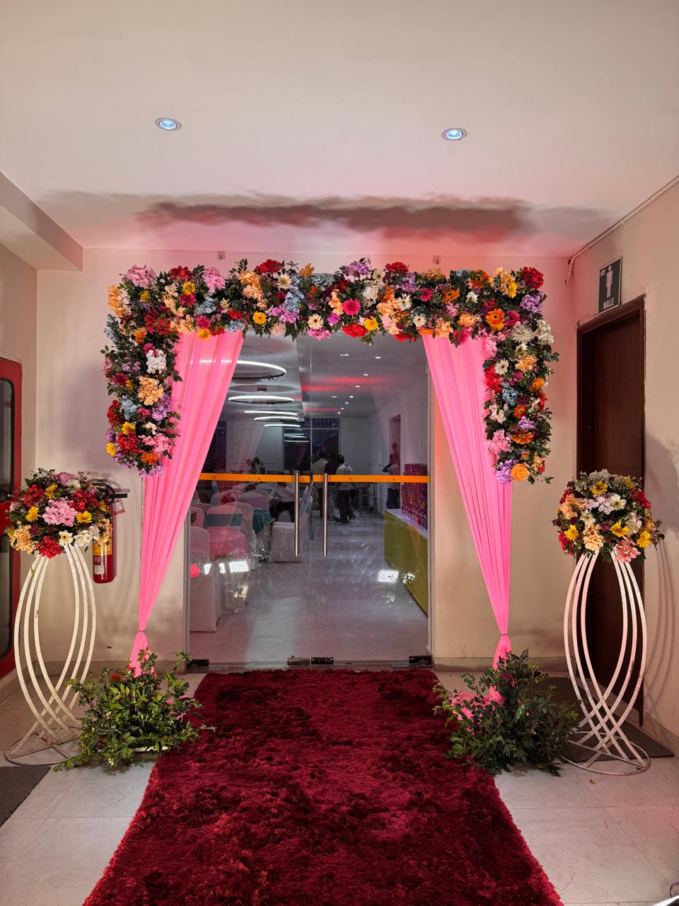 Floral archway entrance with red carpet and draped drapes in Greater Noida