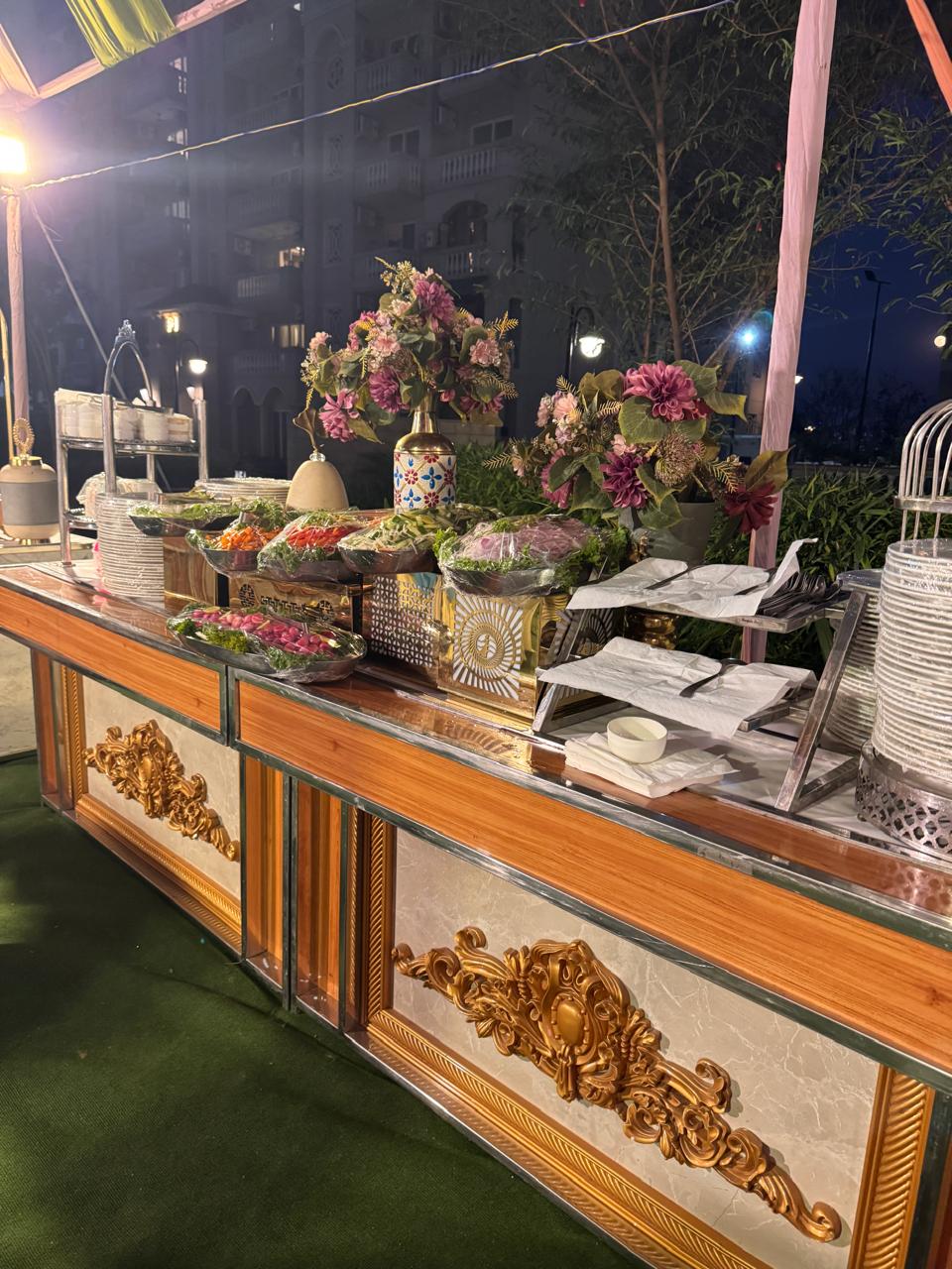 Outdoor evening buffet with floral centerpieces and plated service in Greater Noida